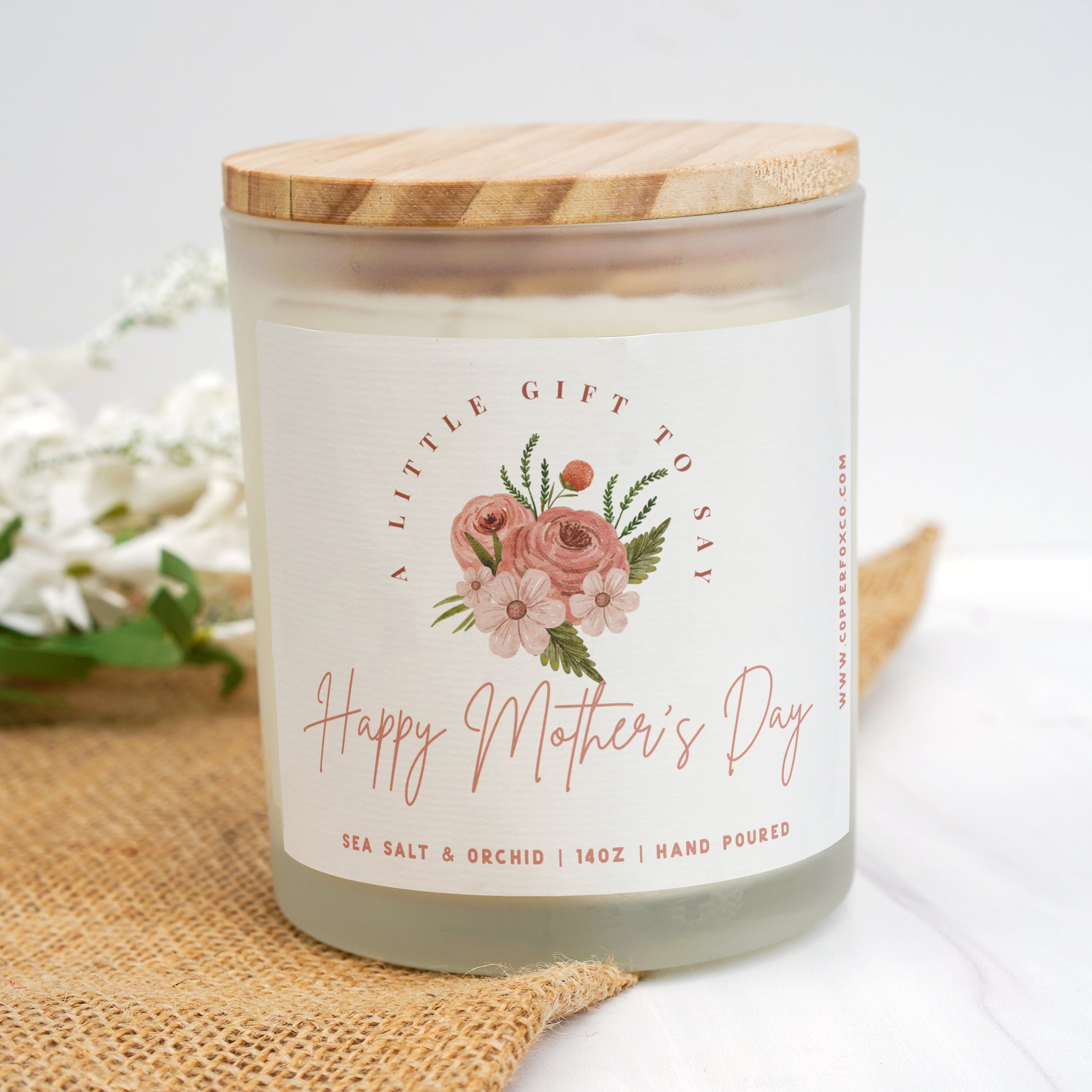 a jar of happy mother's day candle next to flowers